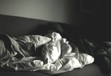 grayscale photography of crumpled blankets on sofa
